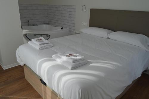 a bedroom with a white bed with towels on it at Apartamentos el Beyu in Cangas de Onís