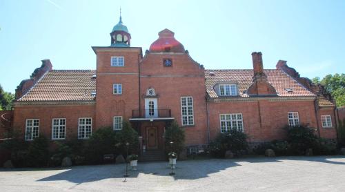 a large red brick building with a clock tower at Sauntehus Castle Hotel in Hornbæk