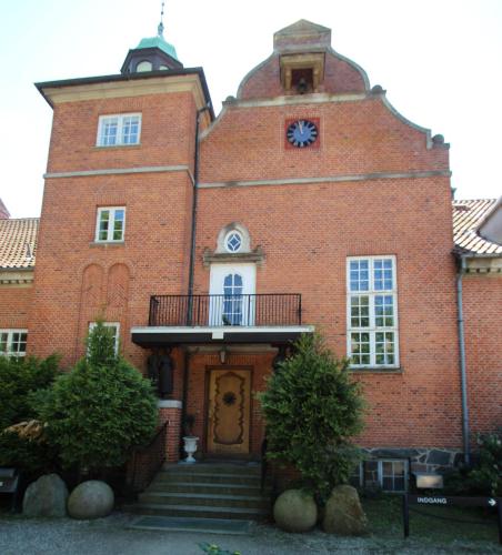 a large red brick building with a clock on it at Sauntehus Castle Hotel in Hornbæk