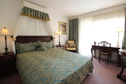a bedroom with a bed and a desk and a window at Sauntehus Castle Hotel in Hornbæk