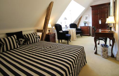 a bedroom with a black and white striped bed and a desk at Sauntehus Castle Hotel in Hornbæk