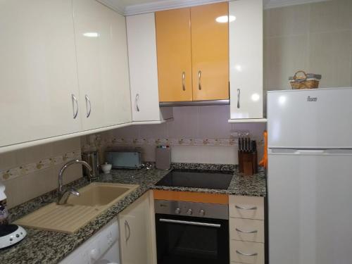 kuchnia z białymi szafkami, zlewem i lodówką w obiekcie Sant Pere 139 Apartments w mieście El Campello