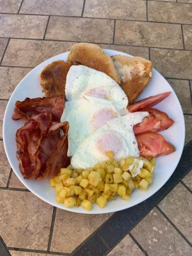 a plate of breakfast food with eggs bacon and toast at Woodslee Bed and Breakfast in Belle River