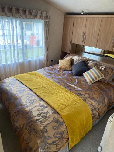 a bedroom with a large bed with a yellow blanket at Port Haverigg Millom in Millom