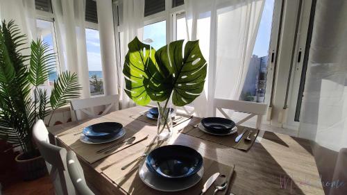 a dining room table with a vase with a plant on it at En la misma playa nuevo 3 dormit vistas al mar in Punta Umbría