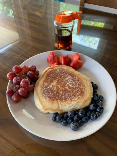 a white plate with pancakes and berries on a table at Woodslee Bed and Breakfast in Belle River