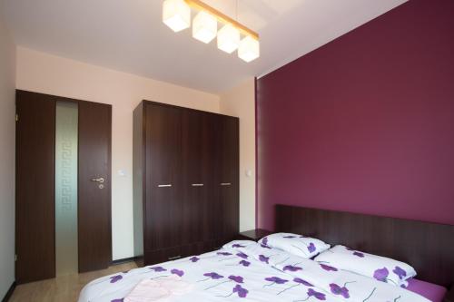 una camera da letto con un grande letto con pareti viola di Słoneczny Apartament a Giżycko