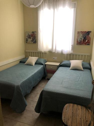 twee bedden in een kamer met een raam bij La casa del 7 in Islantilla