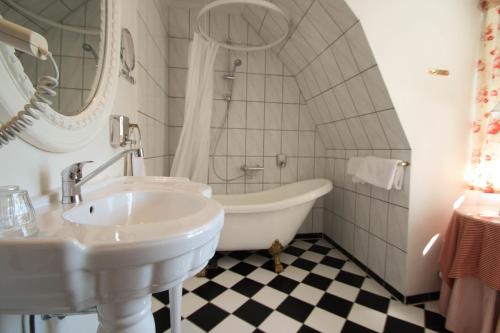 Baño blanco con bañera y lavamanos en Sauntehus Castle Hotel en Hornbæk