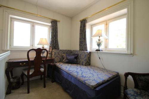 a bedroom with a couch and a desk and two windows at Sauntehus Castle Hotel in Hornbæk