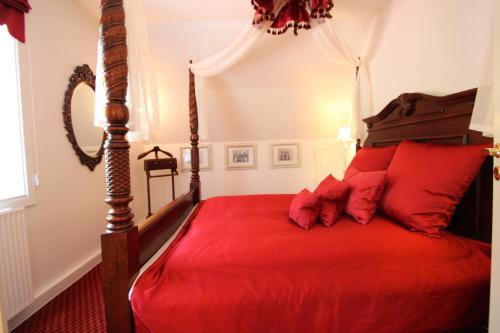 a bedroom with a red bed with red pillows at Sauntehus Castle Hotel in Hornbæk