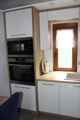a kitchen with white cabinets and a microwave and a sink at Domki Niesiołowice in Niesiołowice