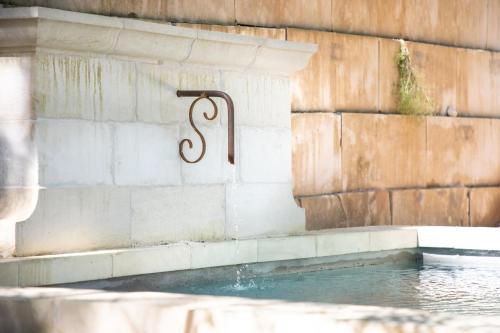 een plas water met een bord op een muur bij Les Cabanes de la Fontaine in Lacoste