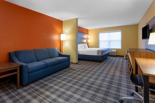 a hotel room with a couch and a bed at AmericInn by Wyndham Fulton Clinton in Fulton