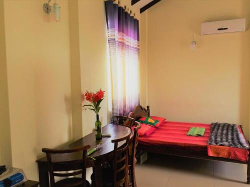 a small room with a table and a red bed at Romeo and Juliet Guest House in Negombo