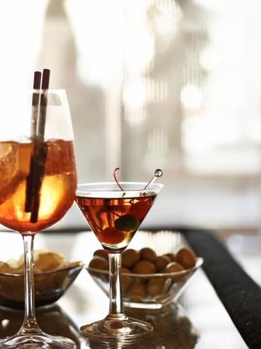 two cocktails sitting on a table with a bowl of peanuts at Grand Hotel De La Ville in Parma