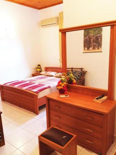 a bedroom with a bed with a dresser and a mirror at Romeo and Juliet Guest House in Negombo