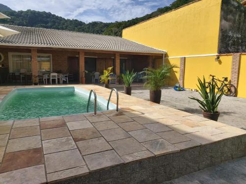 a swimming pool in front of a house at Tudo de Bom in Caraguatatuba