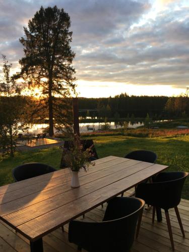 a wooden table and chairs on a deck with the sunset at Projekt Schwedenalm in Furudal