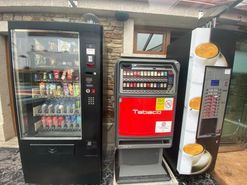a soda vending machine next to a drink cooler at Hotel Rural Finca Aldeola in Malpica