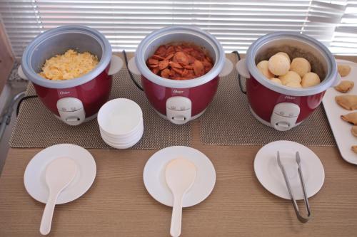 a table with two buckets of food and plates and spoons at Hotel Copacabana Piracicaba in Piracicaba