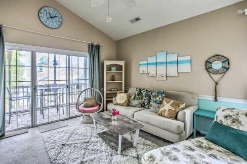 a living room with a couch and a table and a clock at Lovely Myrtle Beach Condo 4 Mi to Boardwalk! in Myrtle Beach