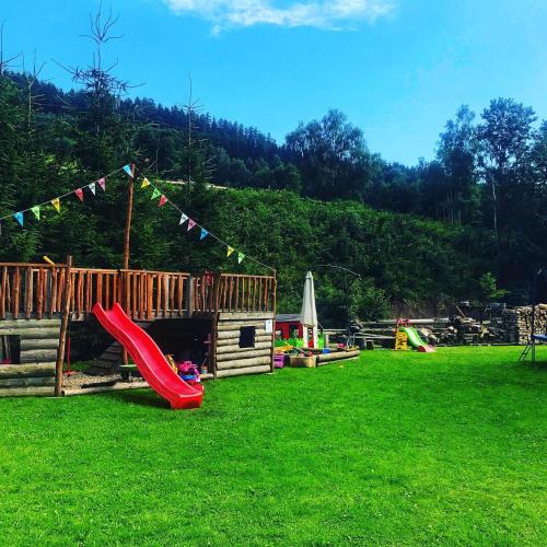 a playground with a slide and a play house at Chata u Cecila in Loučná nad Desnou