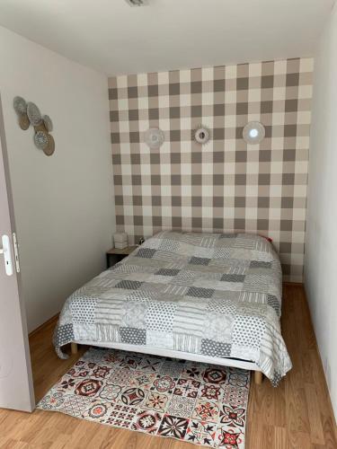 a small bedroom with a bed and a checked wall at Studio indépendant Lisieux in Lisieux