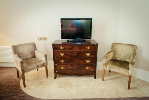 two chairs sitting next to a dresser with a television at Albany House in Dublin