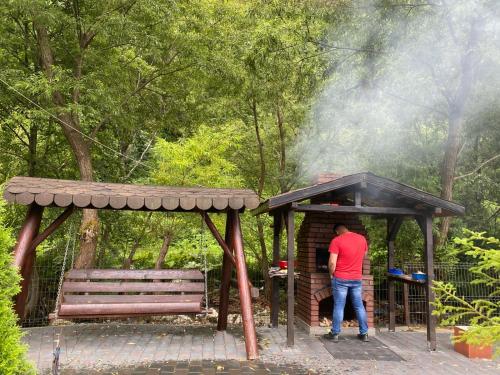 a man standing in a shed next to a bench at Pensiunea Julian House in Moieciu de Jos