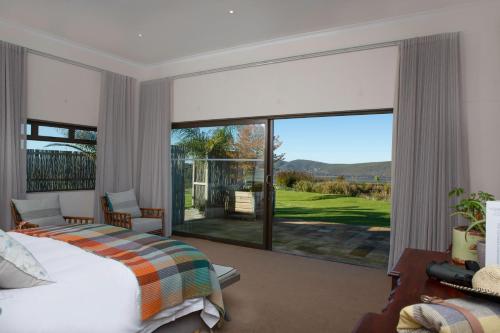 a bedroom with a bed and a large sliding glass door at Hudson Manor - Entabeni, Knysna in Knysna
