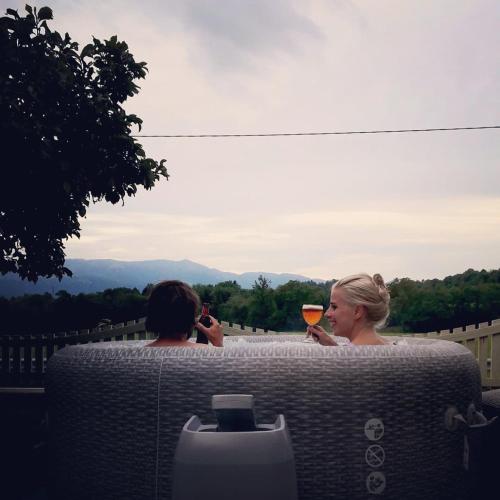two people sitting on a bench with a glass of wine at Dolomitiloungebelluno Mountain resources in Belluno