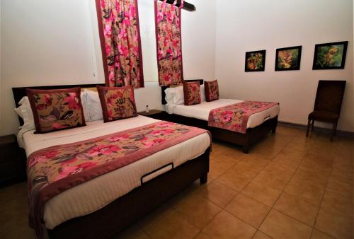 a hotel room with two beds and a chair at Amazilia Hotel in Pereira