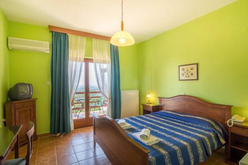 a bedroom with a bed with green walls and a window at Roxani Country House Resort in Maronia