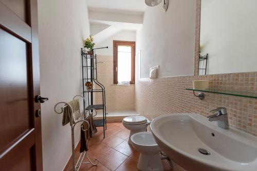 une salle de bain avec un lavabo, des toilettes et un miroir dans l'établissement Country House il Gelso e l’Ulivo, à Noto