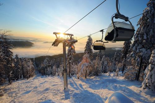 a ski lift going up a snow covered mountain at J-H APARTMÁNY HORSKÝ RESORT BUKOVÁ HORA - 100 m od LANOVKY in Červená Voda