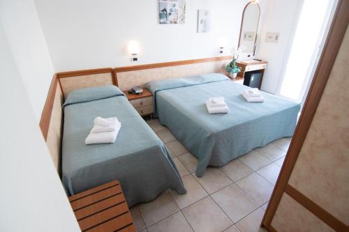 pokój hotelowy z dwoma łóżkami i lustrem w obiekcie HOTEL ADRIA BEACH w Rimini