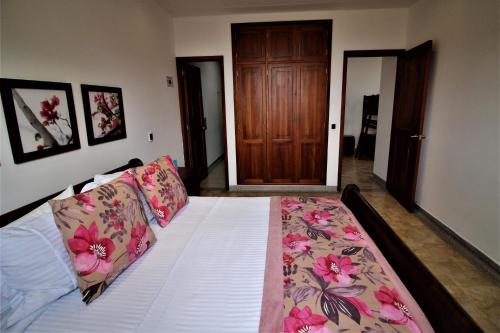 1 dormitorio con 1 cama con sábanas blancas y flores rosas en Amazilia Hotel, en Pereira