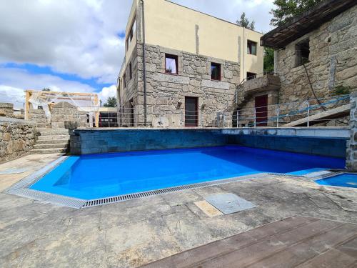 uma grande piscina azul em frente a um edifício em Quinta do Avô - Casa de Campo em Terras de Bouro