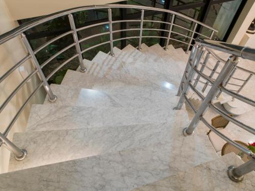 a staircase with white marble floors and a metal railing at Tsue The Palace Flats in Sao Paulo