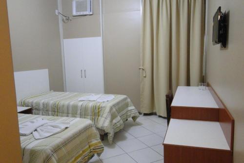 een hotelkamer met 2 bedden en een televisie bij Arrastão Premium Plaza in Muriaé