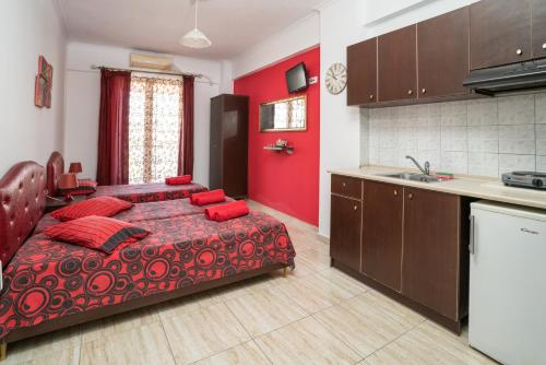 1 dormitorio rojo con 1 cama y cocina en Villa Irida Sun, en Olympiakí Aktí