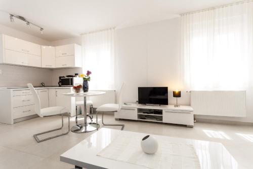 a white living room with a tv and a table at Beach Apartments Rafael in Zadar