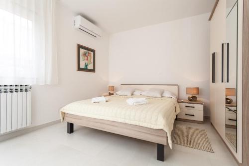 ザダルにあるBeach Apartments Rafaelの白いベッドルーム(大型ベッド1台、鏡付)