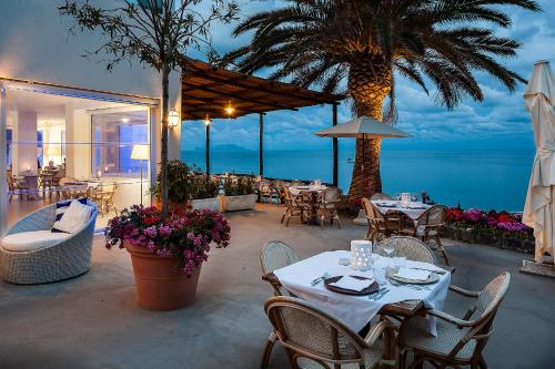 a restaurant with tables and chairs and a view of the ocean at Apollon Club & Thermal Spa in Ischia