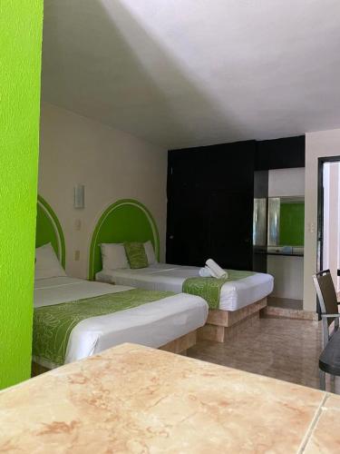 a hotel room with two beds with green walls at HC International by R&T in Cancún