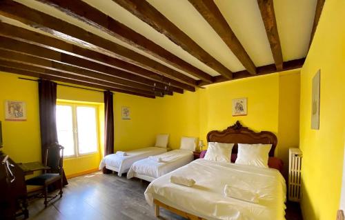 two beds in a room with yellow walls at La Chancellerie in Montrichard