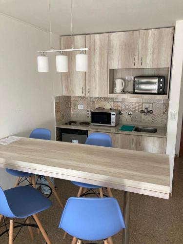 a kitchen with a wooden table and blue chairs at Apart Plaza in Río Cuarto
