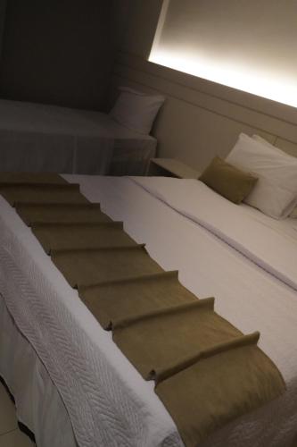 a bedroom with two beds and a white bed with a window at Pak Suítes Hotel in Luis Eduardo Magalhaes