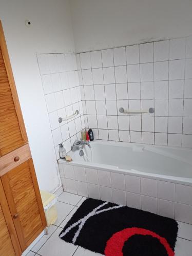 La salle de bains est pourvue d'une baignoire blanche et d'un tapis noir. dans l'établissement Chambre chez l'habitant, à Saint-Dié-des-Vosges